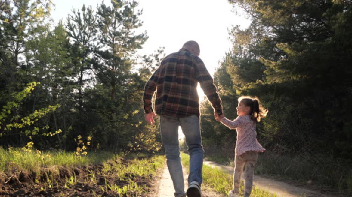 Una piccola mano di bimba stringe la mano grande e rugosa di un nonno.